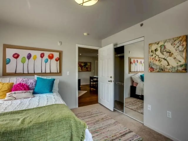 Bed with colorful pillows art mirrored closet bedroom at The Landings at Chandler Crossings in East Lansing Student Accommodation
