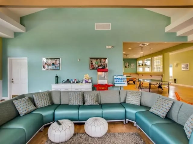 Turquoise sectional couch two ottomans popcorn machine living room at The Landings at Chandler Crossings in East Lansing Student Accommodation