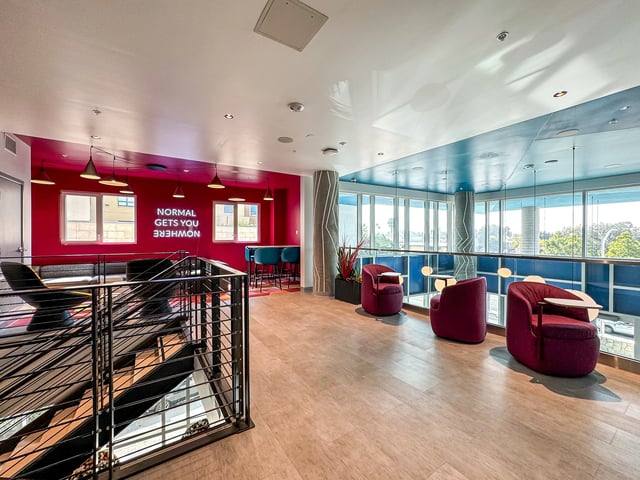 Modern lounge with red accent wall living area at Topaz in San Diego Student Accommodation