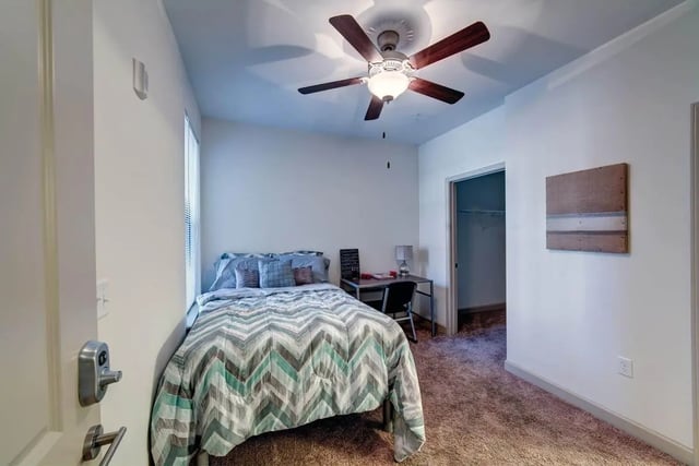 Bed desk chair and ceiling fan bedroom at Riverfront Village in Tuscaloosa Student Accommodation