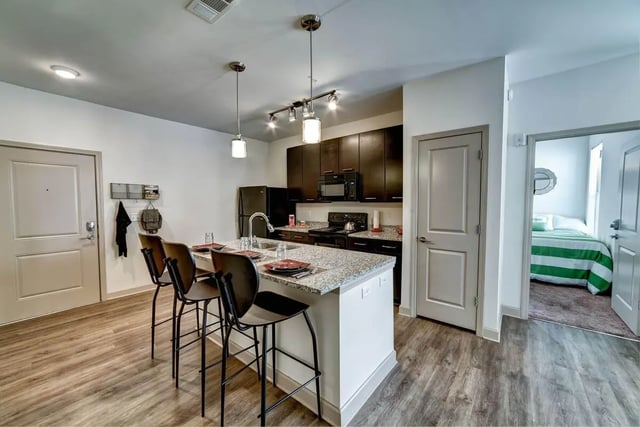 Kitchen island with bar stools and bedroom beyond kitchen at Riverfront Village in Tuscaloosa Student Accommodation