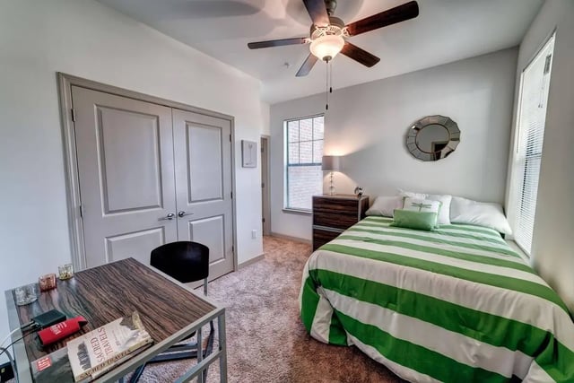 Bed with green stripes dresser and desk Bedroom at Riverfront Village in Tuscaloosa Student Accommodation