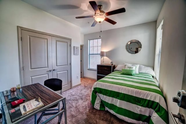 Bed with green white stripes and desk bedroom at Riverfront Village in Tuscaloosa Student Accommodation