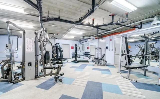 Weight machines dumbbells and a barbell gym area at The Warehouse Apartments Chapel Hill in Chapel Hill Student Accommodation