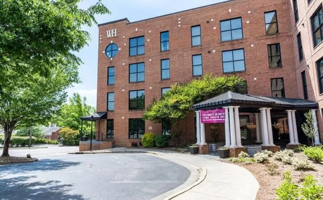 Brick building with large windows and entrance exterior at The Warehouse Apartments Chapel Hill in Chapel Hill Student Accommodation