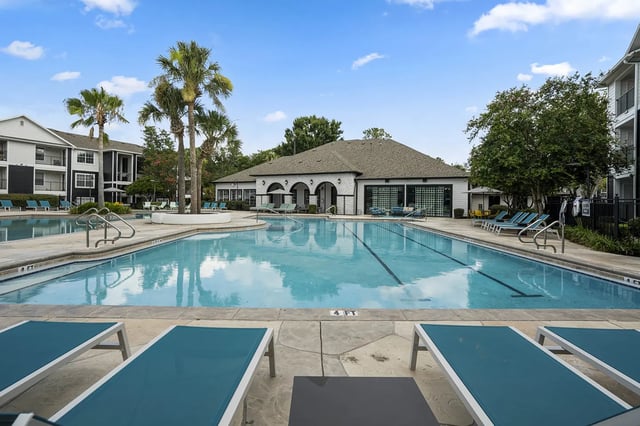 Pool with lounge chairs and palm trees exterior at On20 Apartments in Gainesville Student Accommodation