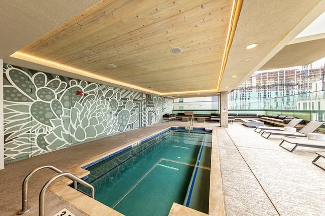Indoor pool with cactus mural lounge seating and lounge chairs pool area at 21 Rio in Austin Student Accommodation