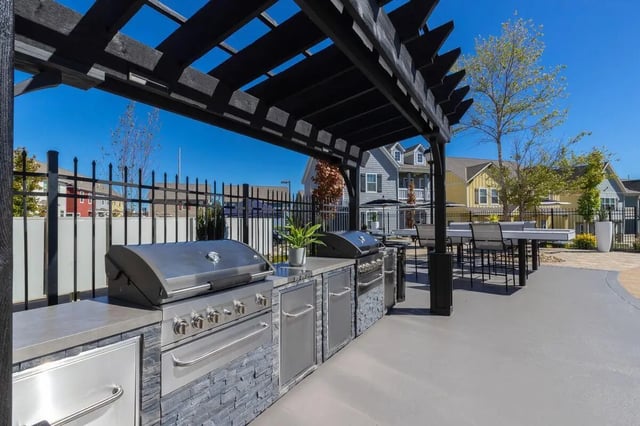 Built-in grills long bar with stools outdoor kitchen at The Collective at Columbia Apartments in Columbia Student Accommodation