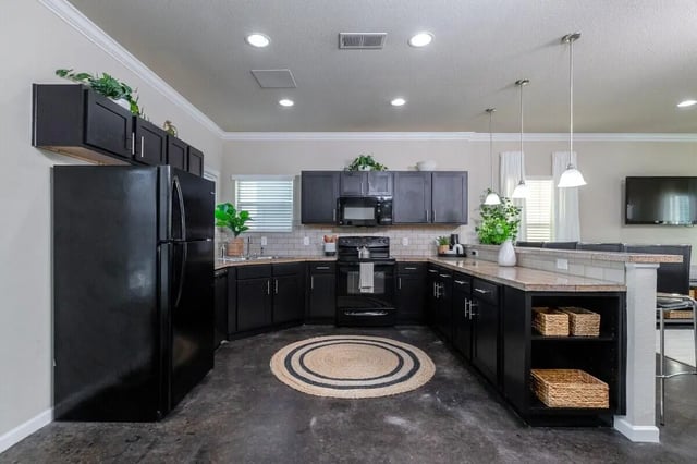 Black cabinets refrigerator stove microwave woven rug kitchen at The Collective at Columbia Apartments in Columbia Student Accommodation