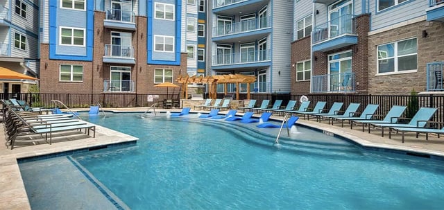 Resort style pool with lounge chairs and buildings Exterior at The Armory in Huntsville Student Accommodation
