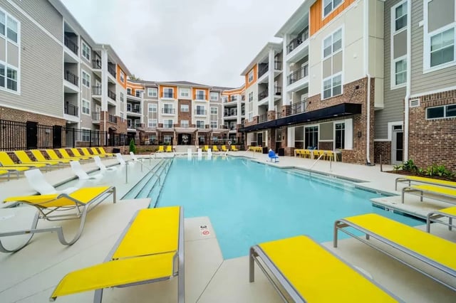 Apartment buildings surrounding a pool with yellow lounge chairs exterior at Eastern on 10th in Greenville Student Accommodation