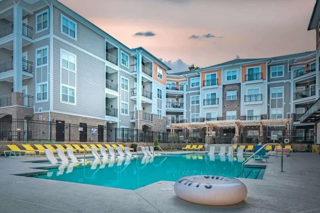 Apartment buildings surrounding turquoise pool with lounge chairs exterior at Eastern on 10th in Greenville Student Accommodation