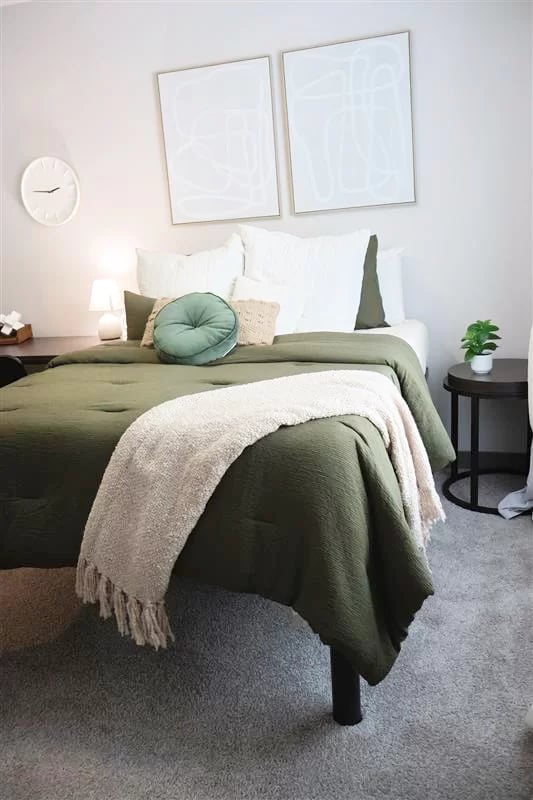 Bed with green bedding white pillows side table bedroom at 200 Edgewood in Atlanta Student Accommodation