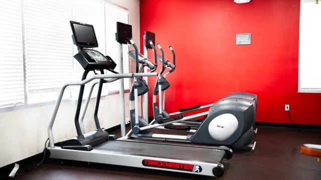 Treadmill elliptical machines on red wall gym area at 1909 Campus Flats in Bowling Green Student Accommodation