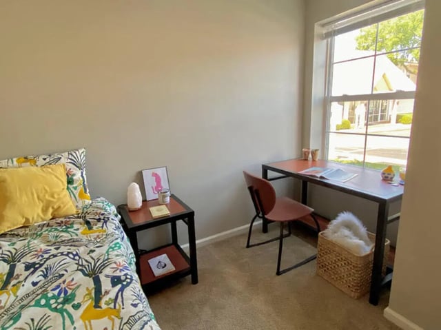 Bed bedside table desk chair and basket bedroom at 1909 Campus Flats in Bowling Green Student Accommodation