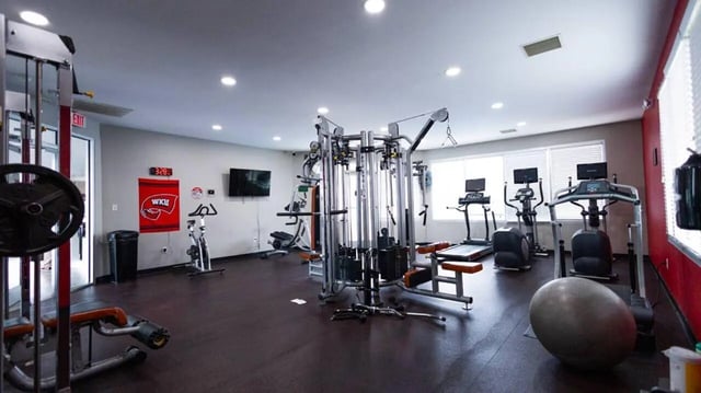 Gym equipment treadmills ellipticals weight machine workout area at 1909 Campus Flats in Bowling Green Student Accommodation