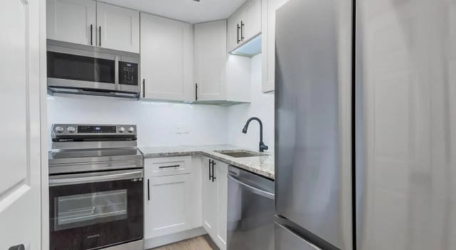 White cabinets microwave stove sink dishwasher refrigerator kitchen at Mint Urban Infinity in Denver Student Accommodation