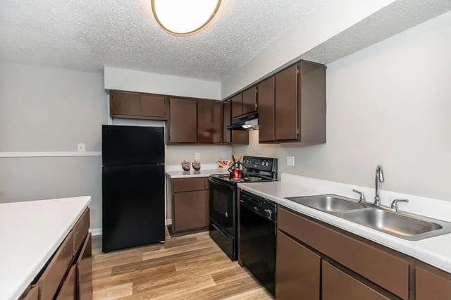 Black refrigerator stove sink kitchen cabinets kitchen at Villas De La Plaza in Austin Student Accommodation