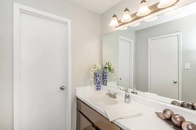 White door sink and vanity with decor Bathroom at Villas De La Plaza in Austin Student Accommodation