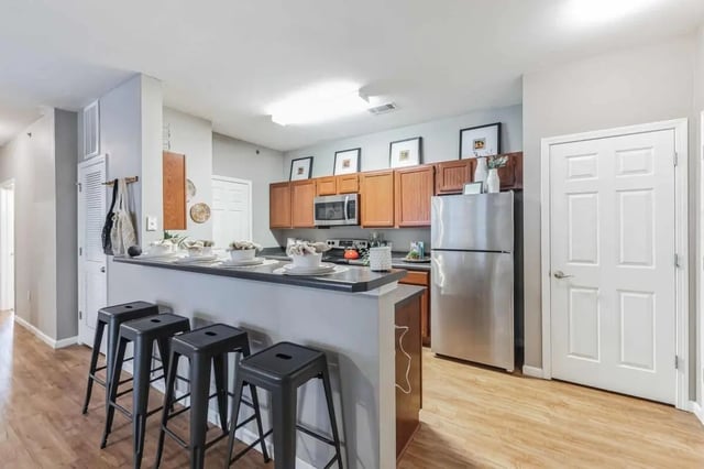 Four black stools facing kitchen island with dishes kitchen at Hill Place in Fayetteville Student Accommodation