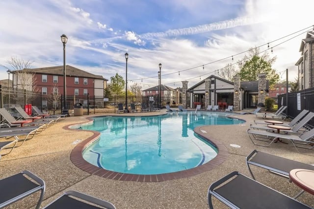 Pool with lounge chairs and buildings exterior at Hill Place in Fayetteville Student Accommodation