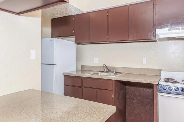 White refrigerator dark cabinets sink stove kitchen at Villas Del Solamar in Dallas Student Accommodation