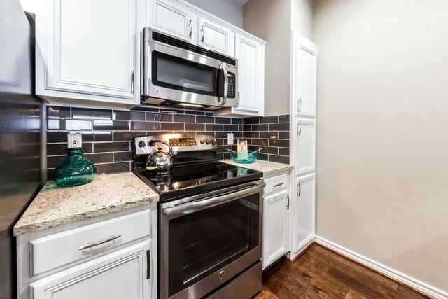 Stainless steel oven microwave white cabinets black tile kitchen at Vines at Turtle Creek in Dallas Student Accommodation