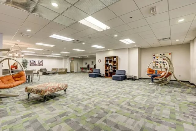 Lounge chairs, ottoman, artwork, and bookshelf common area at Dwell The Towers on State in Madison Student Accommodation