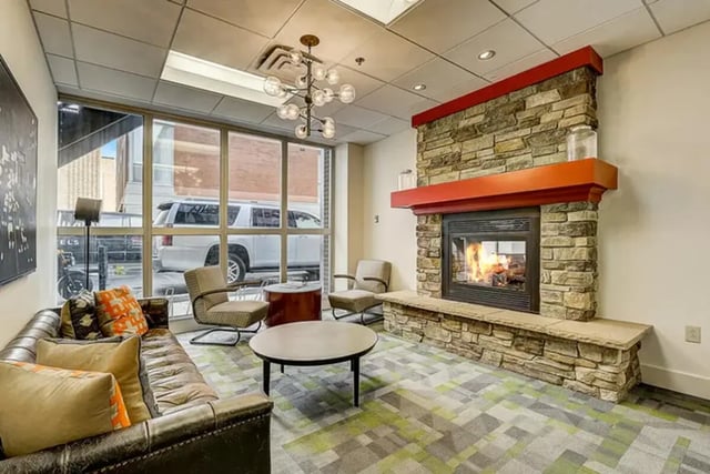 Leather sofa stone fireplace modern chandelier living room at Dwell The Towers on State in Madison Student Accommodation
