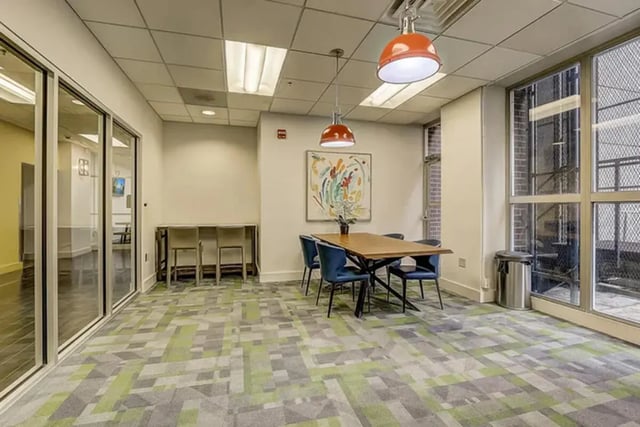 Dining table chairs painting and trash can communal area at Dwell The Towers on State in Madison Student Accommodation