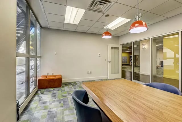 Wooden table chairs orange ottoman communal area interior at Dwell The Towers on State in Madison Student Accommodation