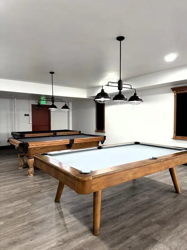 Two pool tables wood floors hanging lights playing area at University Village Fullerton in Fullerton Student Accommodation