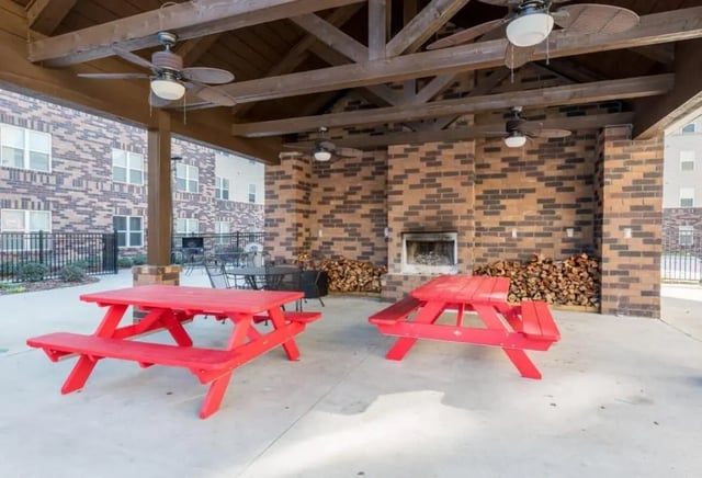 Red picnic tables and fireplace outdoor area at Varsity House Gainesville in Gainesville Student Accommodation