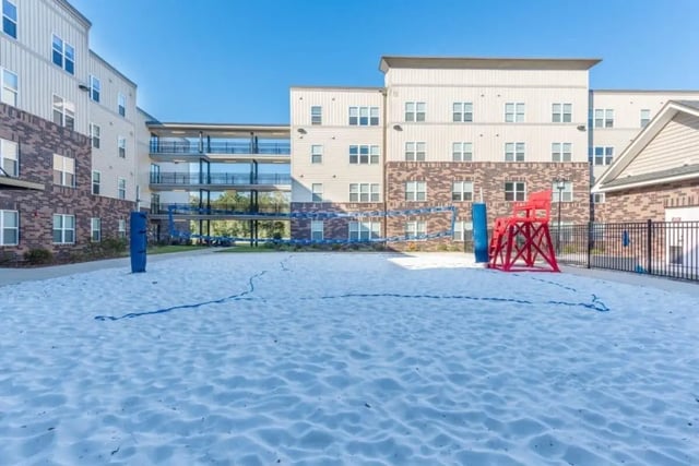 Sand volleyball court with buildings and lifeguard chair exterior at Varsity House Gainesville in Gainesville Student Accommodation
