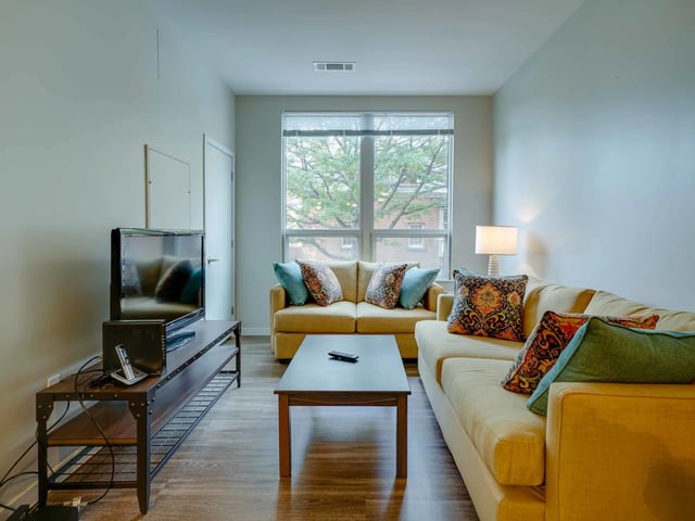Tan sofas coffee table TV unit and window living room at College and Crown in New Haven Student Accommodation