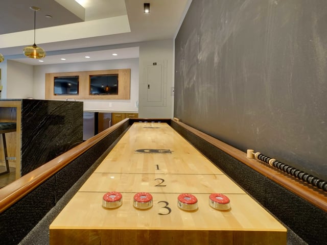 Shuffleboard table with pucks and scoring area game room at College and Crown in New Haven Student Accommodation