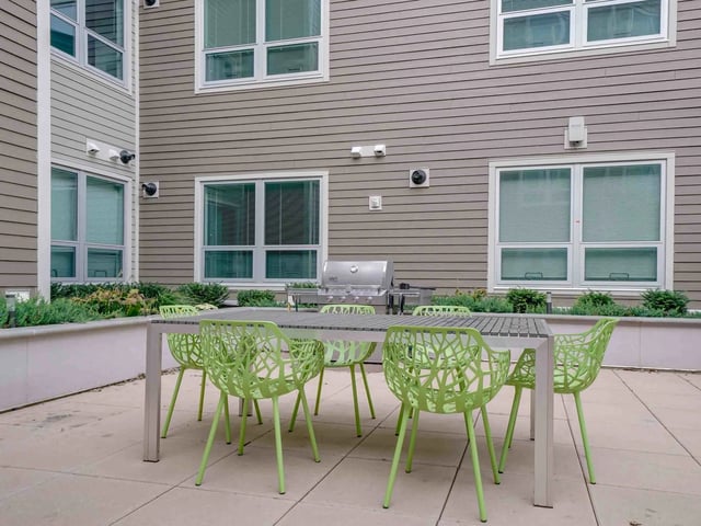 Grill table and lime green chairs outdoor patio area at College and Crown in New Haven Student Accommodation