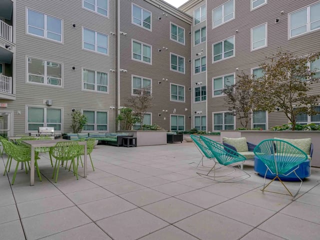Outdoor patio with chairs grill and seating area exterior at College and Crown in New Haven Student Accommodation