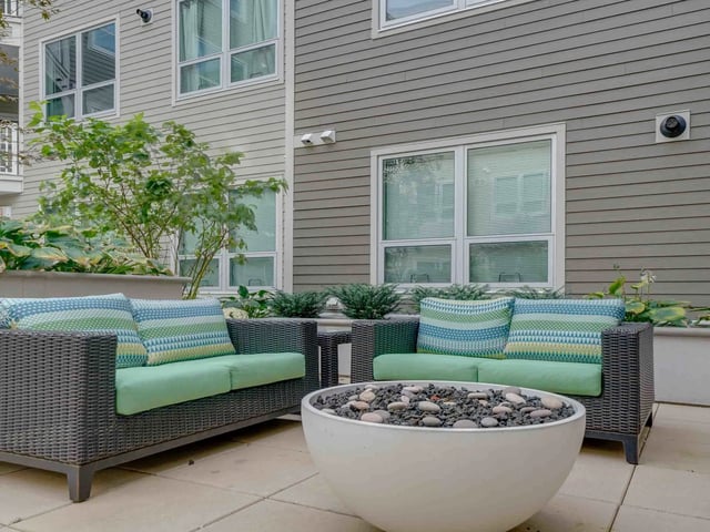 Wicker sofas with green cushions fire pit living area exterior at College and Crown in New Haven Student Accommodation