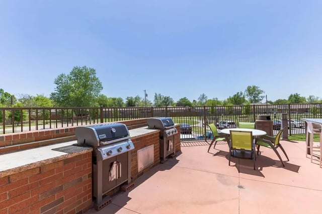 Two grills tables chairs and trash bin outdoor area at Millennium in Norman Student Accommodation