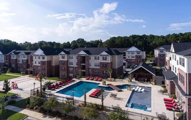 Apartment buildings pool lounge chairs volleyball court exterior at Grove at Auburn in Auburn Student Accommodation