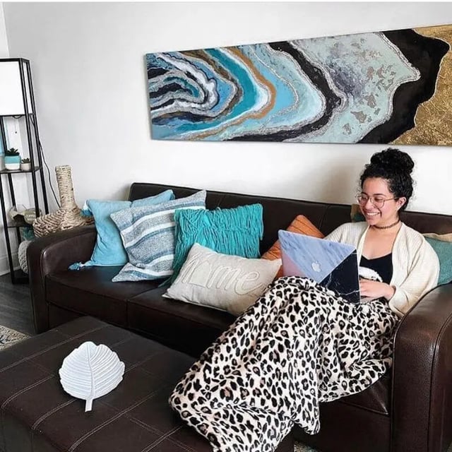Woman using laptop on couch with pillows living room at Copper Beech Townhomes - Ames in Ames Student Accommodation