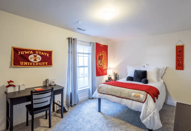 Bed desk chair Iowa State flags bedroom at Copper Beech Townhomes - Ames in Ames Student Accommodation