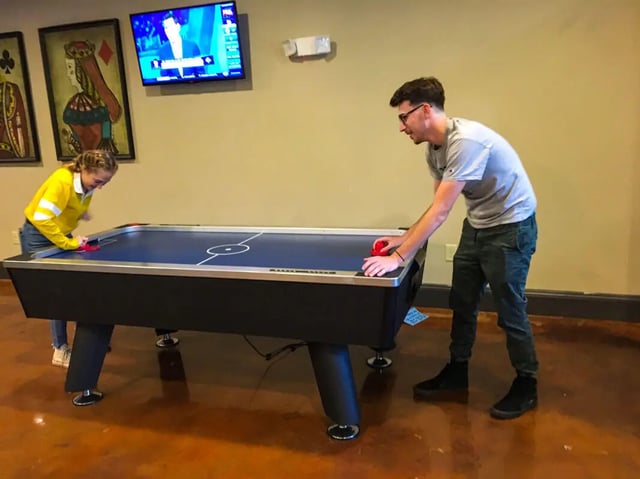 Two people play air hockey table playing area at Grove at Slippery Rock in Slippery Rock Student Accommodation