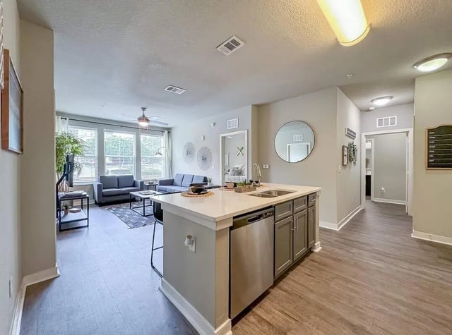 Modern kitchen island with sink and living room area Living room at NXNW in Tallahassee Student Accommodation