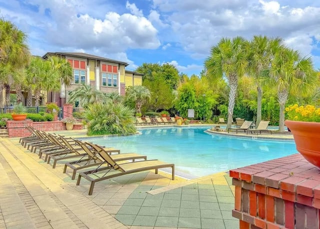 Pool lounge chairs building palm trees exterior at NXNW in Tallahassee Student Accommodation