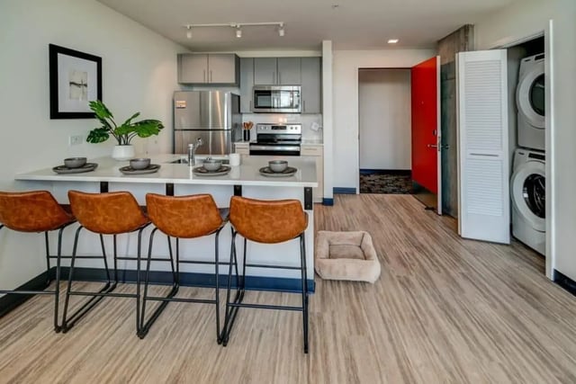 Kitchen island with stools appliances and washing machine kitchen at Chapter at Madison in Madison Student Accommodation
