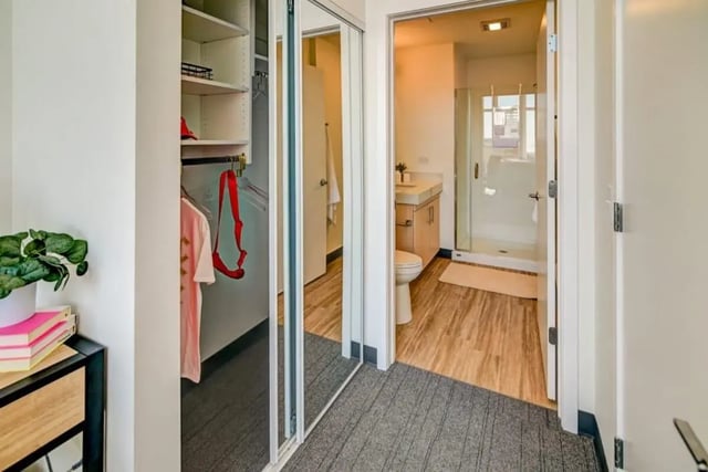 Closet with clothes and mirrored doors leads to bathroom at Chapter at Madison in Madison Student Accommodation