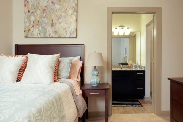 Bed with pillows lamp and doorway to bathroom Bedroom at The Lofts at City Center in Tuscaloosa Student Accommodation