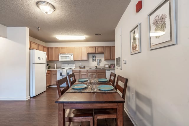 Dining table chairs refrigerator stove cabinets kitchen at Revelry Flats at Milledgeville in Milledgeville Student Accommodation